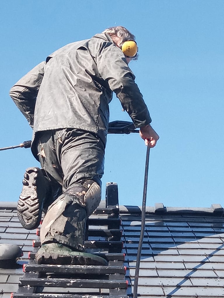 Traitement hydrofuge toiture Angers Professionnel appliquant un traitement hydrofuge sur une toiture en ardoise près d'Angers avec matériel de protection